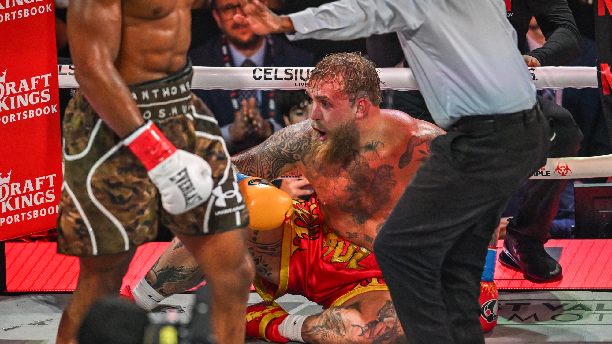 Christopher Young bíró számol az amerikai bokszoló és influencer Jake Paul felett, aki a padlón ül a brit bokszoló Anthony Joshua (balra) elleni, nem címért folyó nehézsúlyú mérkőzésen a floridai Miami Kaseya Centerben.