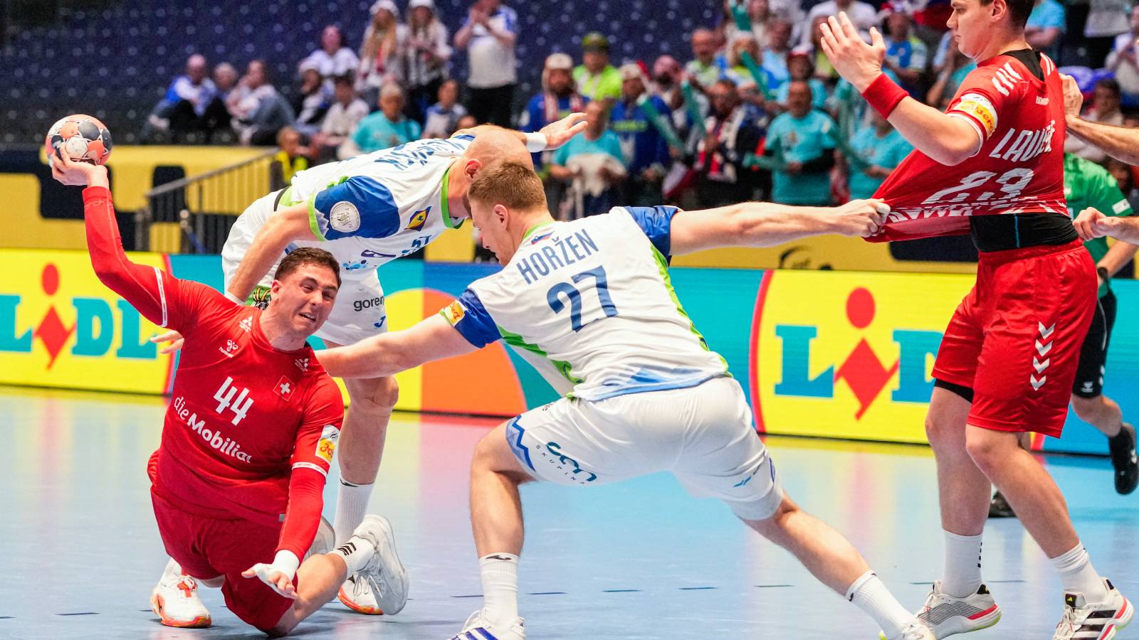 Switzerland's left back #44 Mehdi Ben Romdhane (L), Switzerland's pivot #23 Lukas Laube (R) and Slovenia's pivot #27 Kristjan Horzen (C) vie for the ball during the men's EHF Euro 2026 preliminary round handball match Switzerland vs Slovenia in Oslo, Norway, on January 18, 2026.