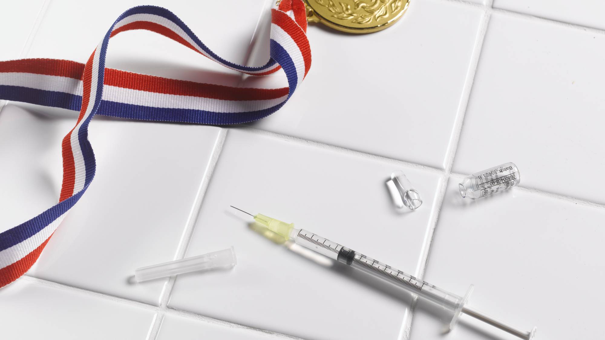 . Medal and syringe on tiled floor - stock photo