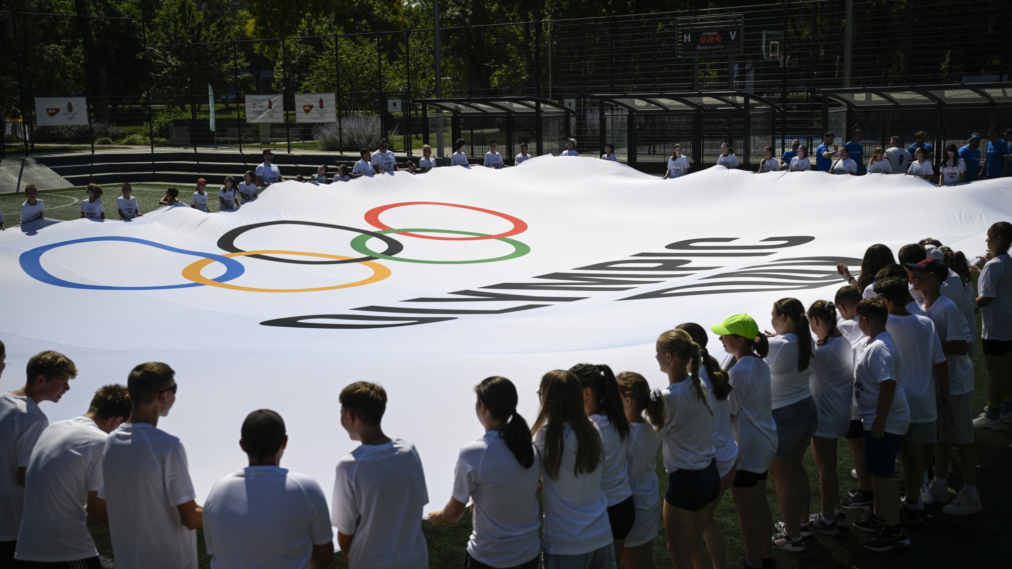 Résztvevők a rendezvény zászlóját feszítik ki az Olimpia Napja alkalmából rendezet családi sportnapon a Városligetben.