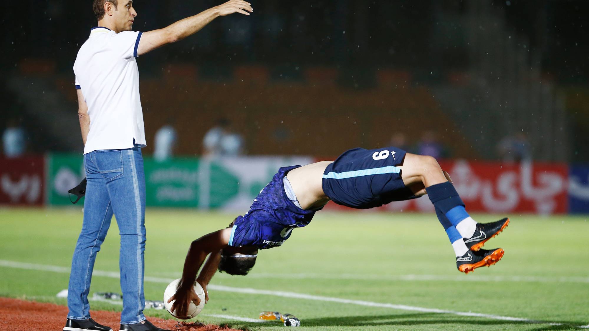 TEHRAN, IRAN - JULY 31: (BILD ZEITUNG OUT) head coach Yahya Golmohammadi of Persepolis looks on, Nader Mohammadi of Peykan does a somersault throw-in during the Persian Gulf Pro League Match between Paykan and Persepolis at Shahr-e Qods Stadium on July 31, 2021 in Tehran, Iran. (Photo by Mohammad Karamali/DeFodi Images via Getty Images)