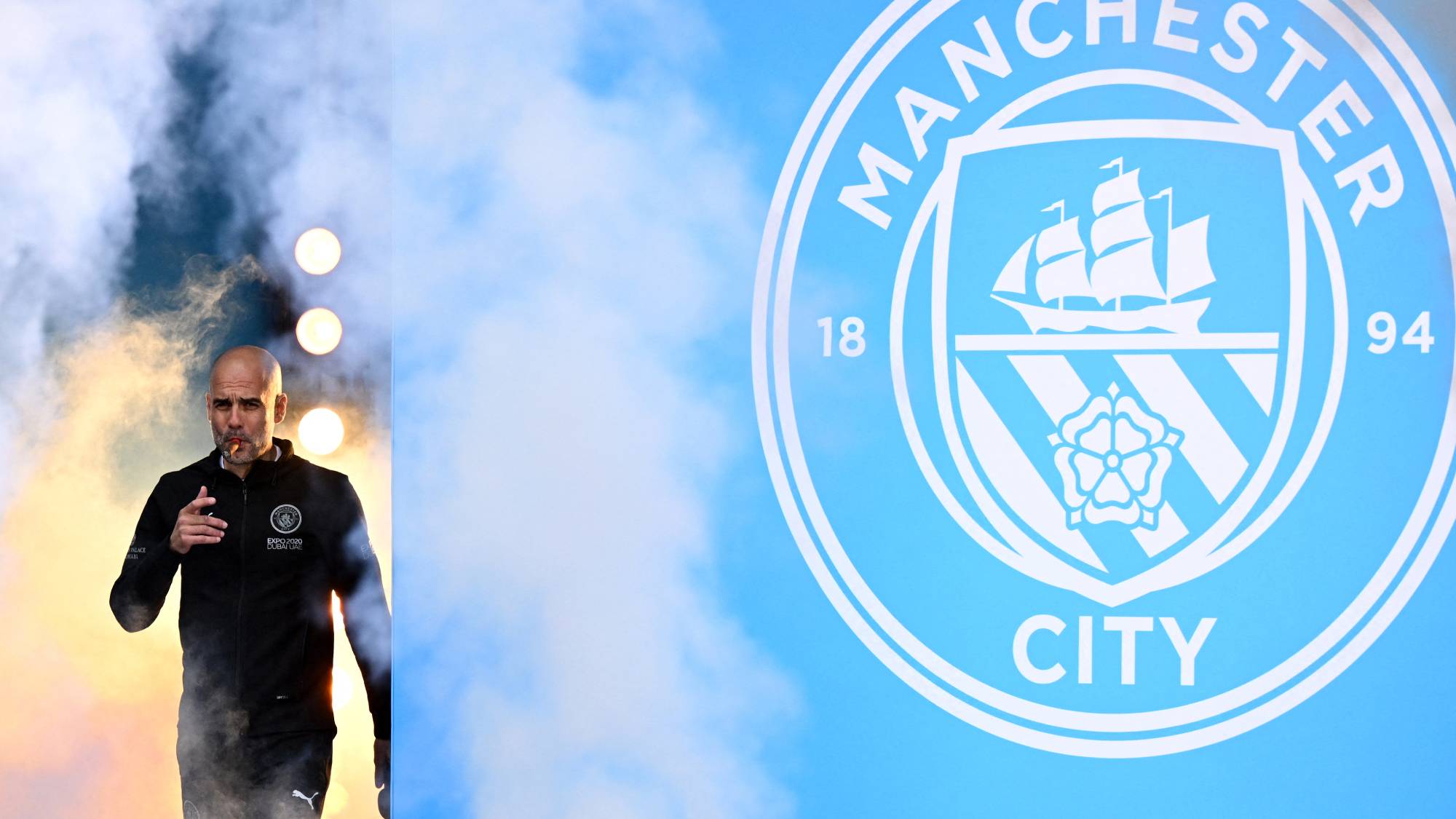 Manchester City's Spanish manager Pep Guardiola smokes a cigar as he attends an event for fans with members of the Manchester City football team following an open-top bus parade through Manchester, north-west England on May 23, 2022, to celebrate winning the 2021-22 Premier League title. Pep Guardiola voiced his strong support for Manchester City on September 30, 2026 after the club were found guilty of more than 100 breaches of Premier League financial rules.