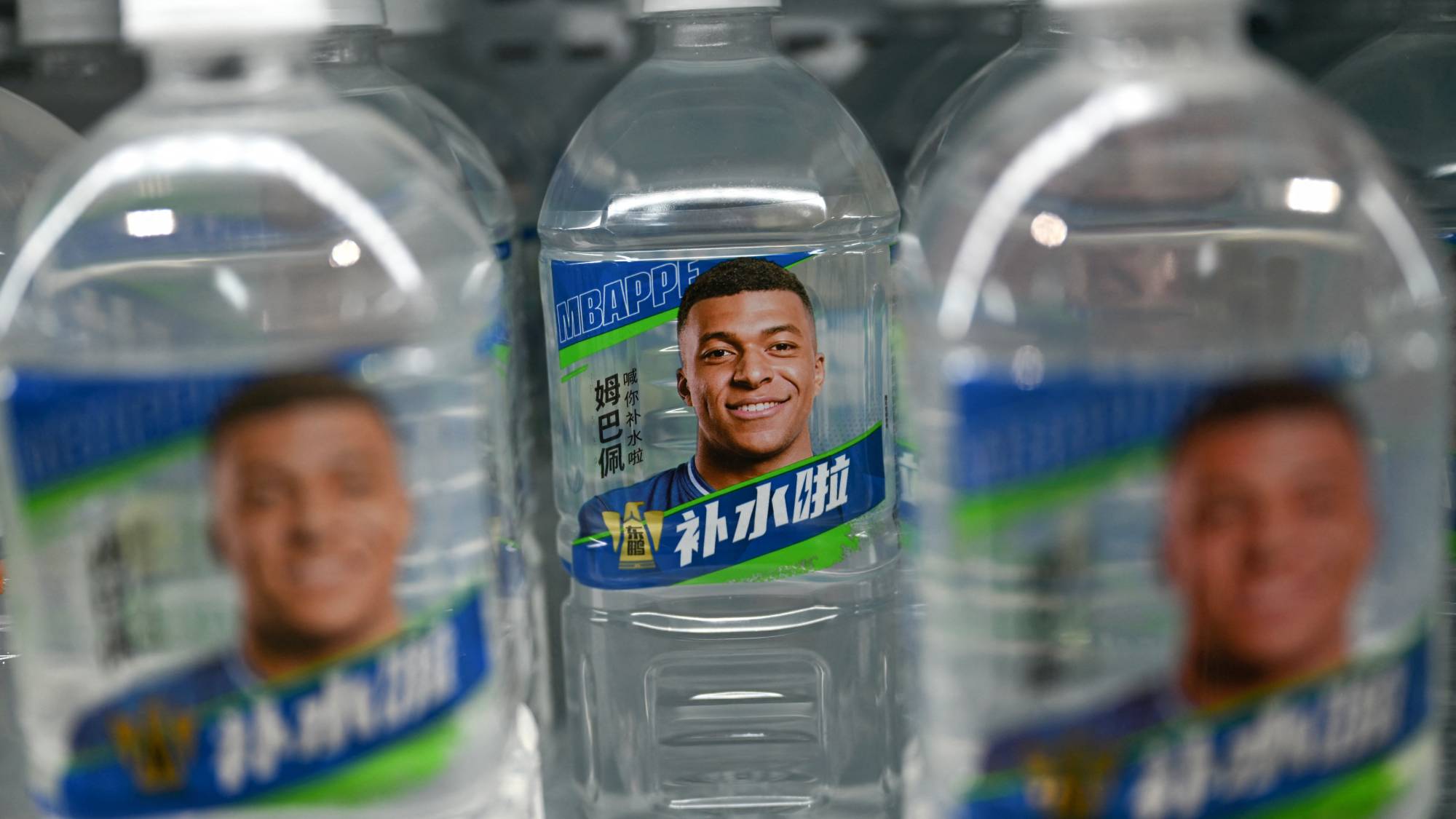 Bottles of Dongpeng Beverage Group's "Bushuila" electrolyte drink featuring French football star Kylian Mbappe on the packaging are displayed at a convenience store in Beijing on October 27, 2026. Kylian Mbappe was dropped October 27 by two major brands in China after a video circulated online in which the French football star apparently joked about former leader Mao Zedong.